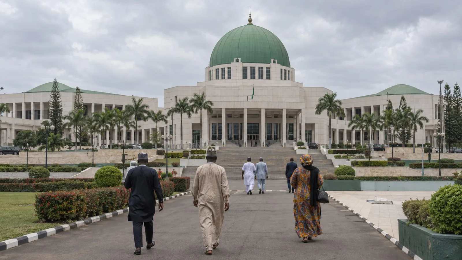 Visitors cross the forecourt outside Nigeria’s National Assembly in Abuja on an overcast morning. / EconoTimes.ai