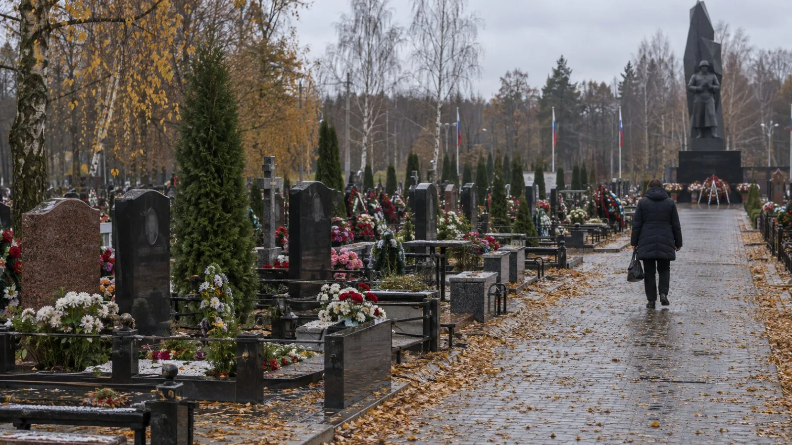 A visitor walks past soldiers’ graves in Pavlovsky Posad, Russia. (AI-generated image / EconoTimes)