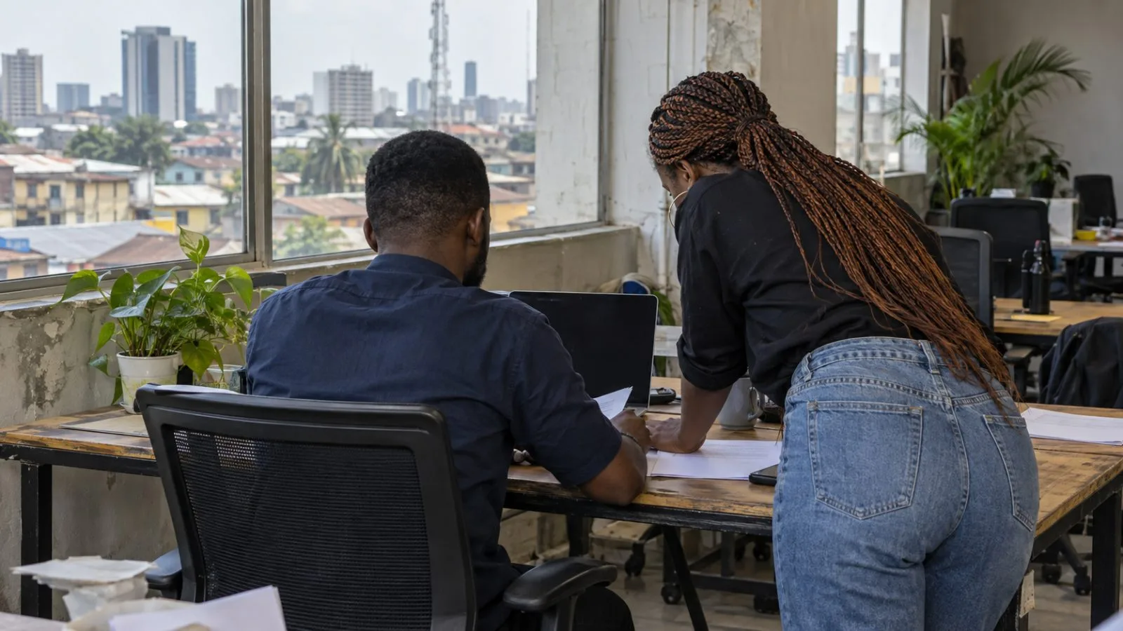 Startup workers review expenses on a laptop in Lagos's Yaba district. (AI-generated image / EconoTimes)