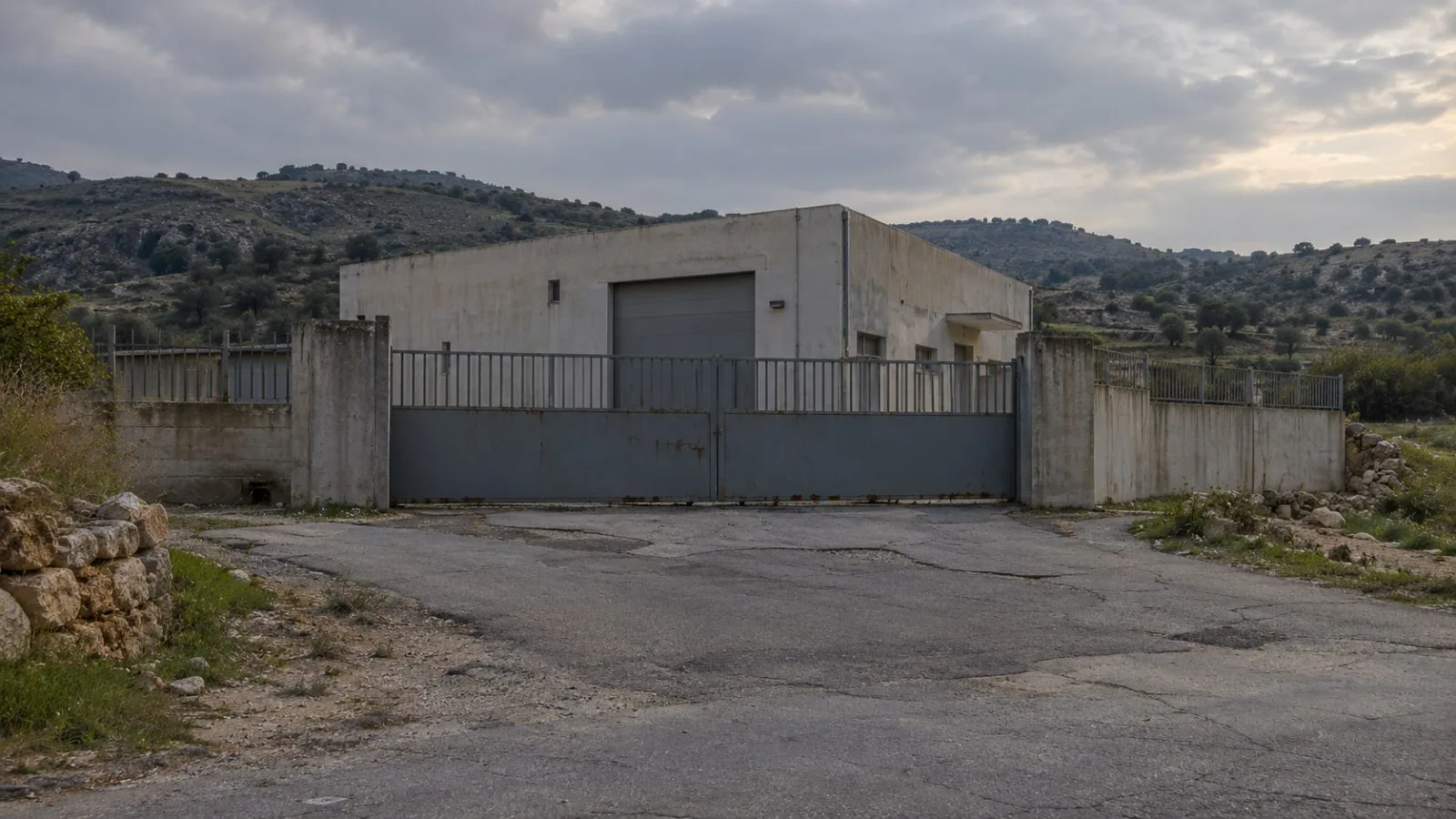 A closed concrete facility sits behind a metal gate in Kfarra, southern Lebanon. (AI-generated image / EconoTimes)