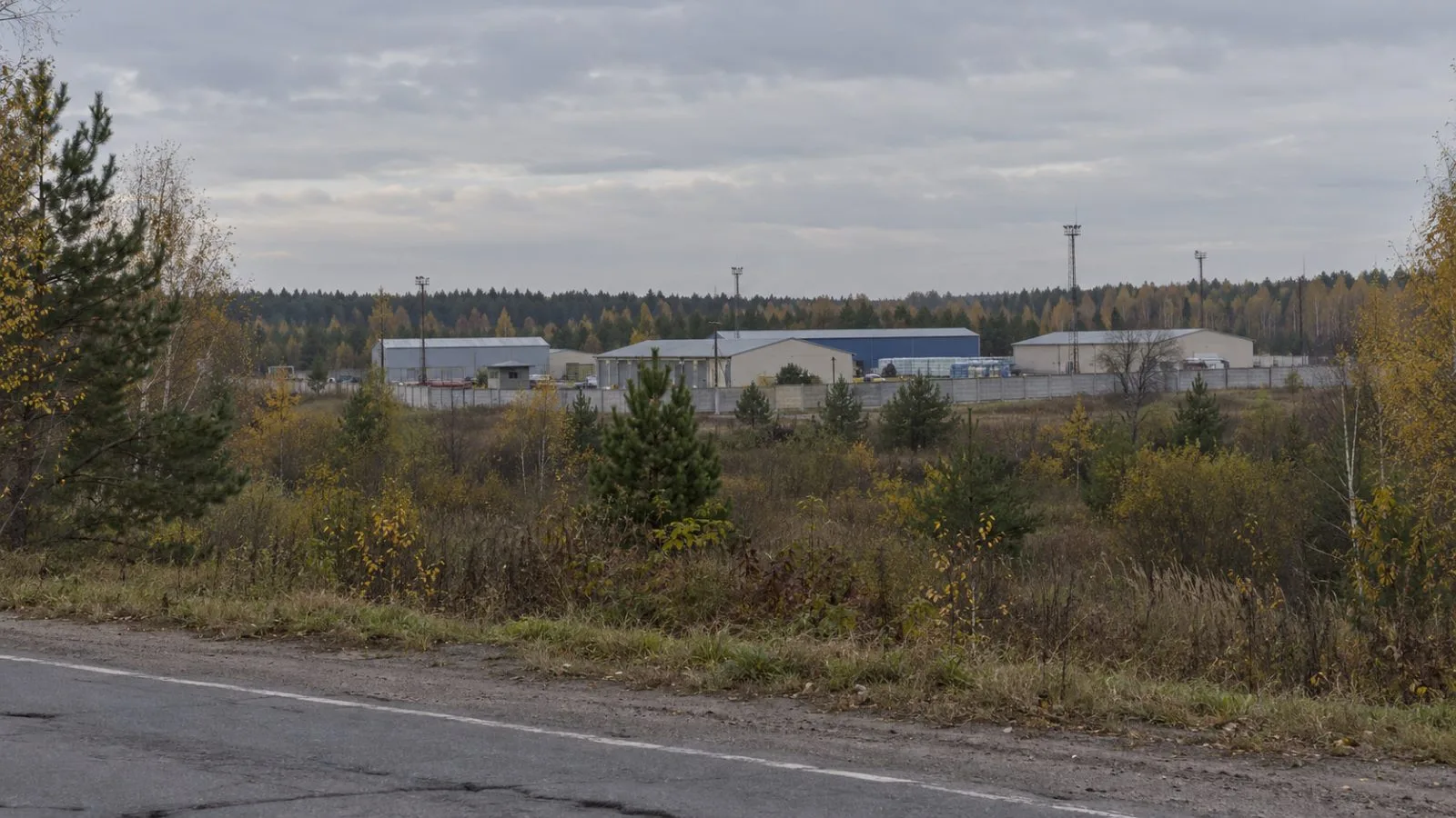 A fenced industrial compound stands among autumn trees on the outskirts of Navlya, Bryansk Oblast (AI-generated image / EconoTimes)