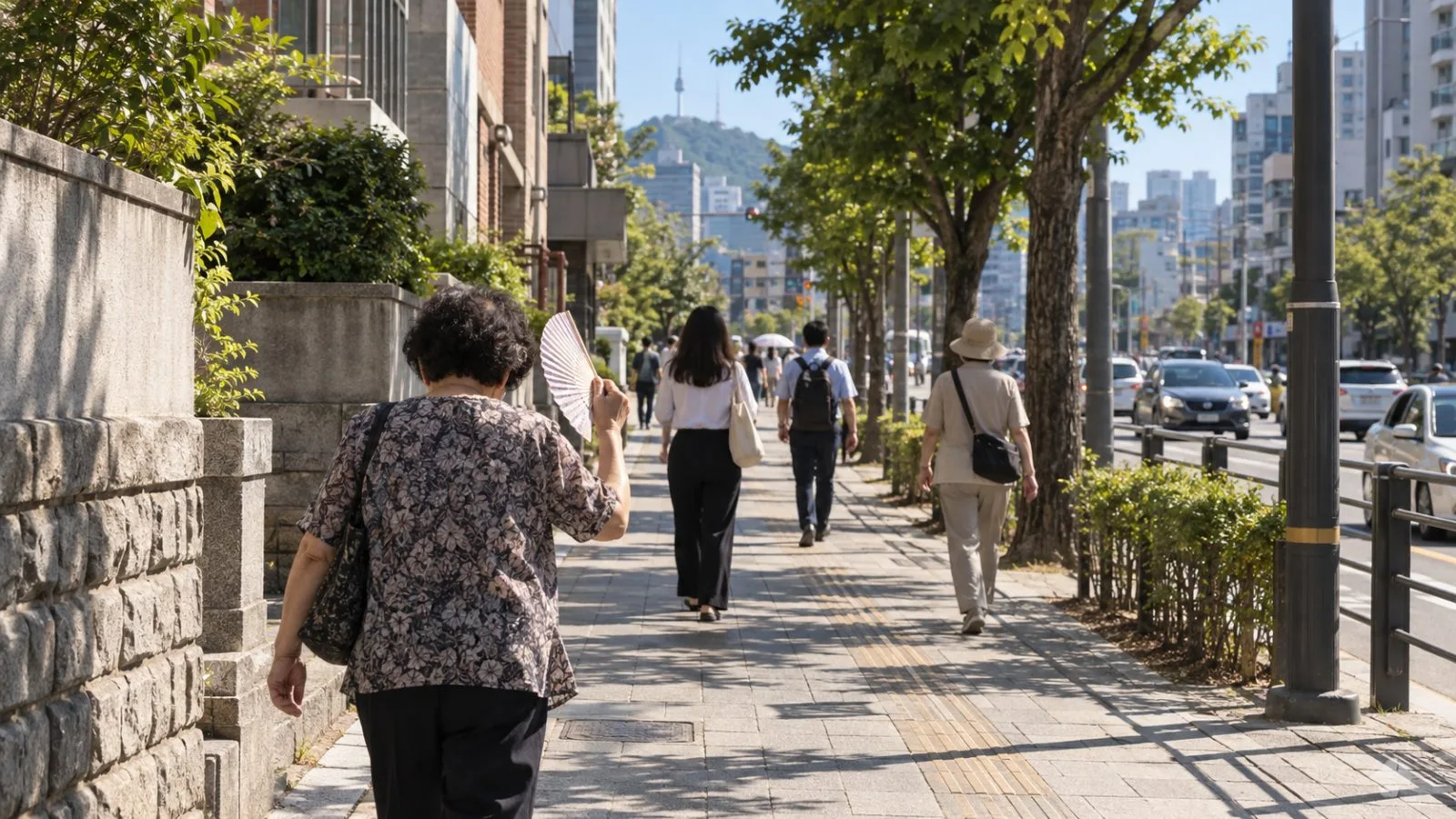 An older pedestrian fans themselves beneath sparse tree shade on a sunlit Seoul sidewalk. (AI-generated image / EconoTimes)
