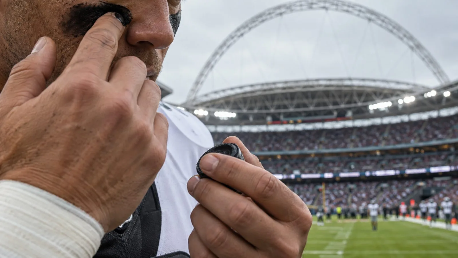 A football player applies eye black before a game at Wembley Stadium in London. (AI-generated image / EconoTimes)