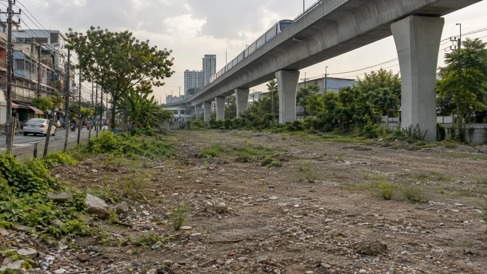 An undeveloped plot sits beside the elevated BTS Sukhumvit Line in Bang Na, Bangkok. (AI-generated image / EconoTimes)