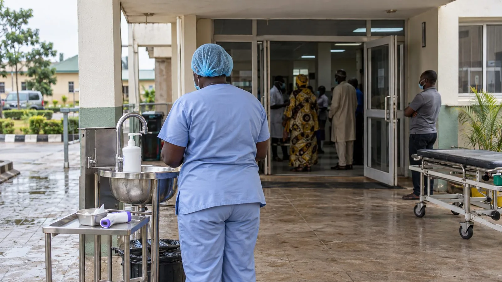 A thermometer and handwashing station stand beside a hospital entrance in Abuja, Nigeria. (AI-generated image / EconoTimes)
