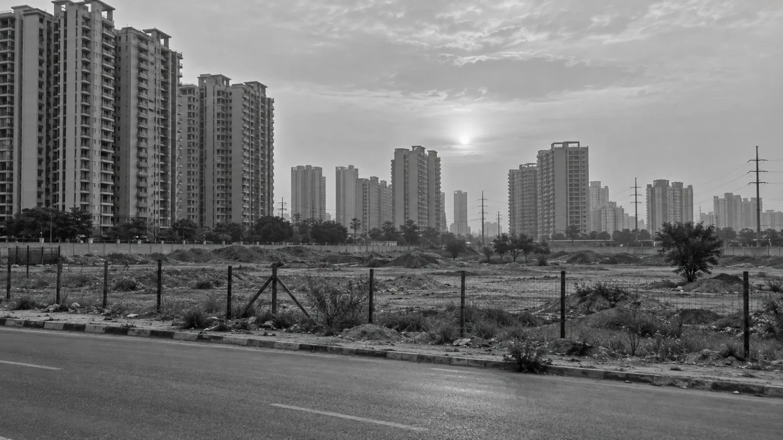 A fenced development parcel sits beside residential towers in Gurugram’s Sector 78, India. (AI-generated image / EconoTimes)
