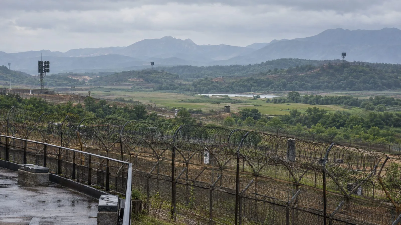Border fencing and distant loudspeakers stand near the Demilitarized Zone in Paju, South Korea. (AI-generated image / EconoTimes)