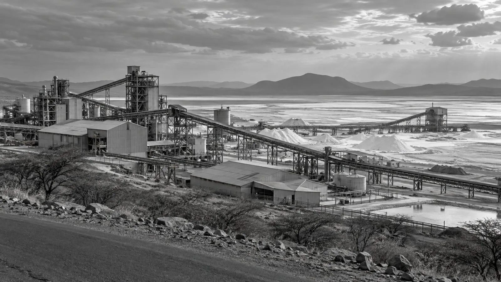 Conveyor belts and processing structures stand beside mineral flats near Lake Magadi, Kenya. (AI-generated image / EconoTimes)