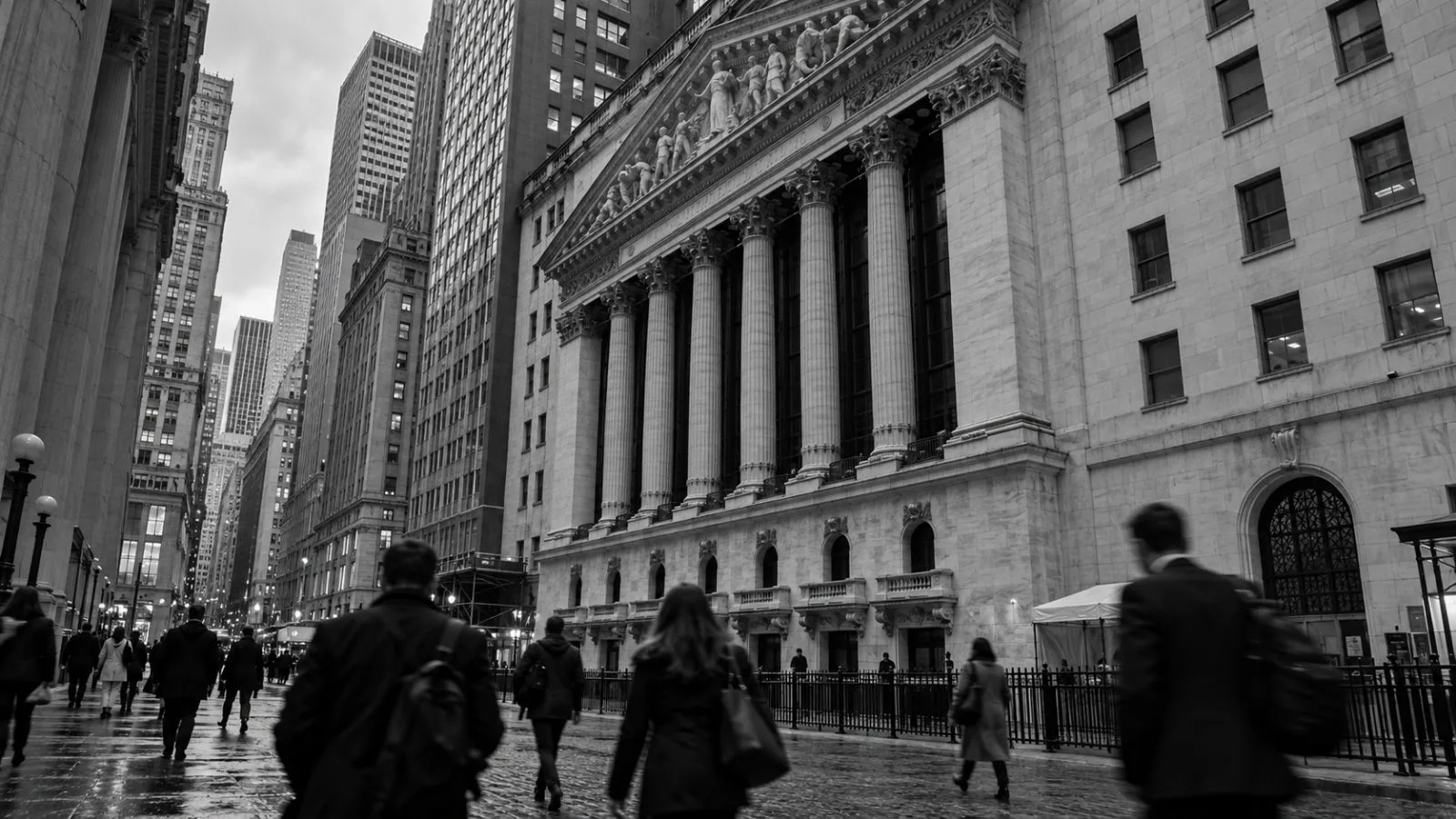 Pedestrians pass the Nasdaq MarketSite in Times Square, New York, beneath a gray afternoon sky. / EconoTimes.ai (mono)