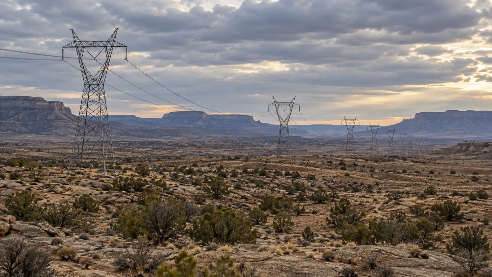 High-voltage transmission lines cross an open utility corridor near Farmington, New Mexico. (AI-generated image / EconoTimes)