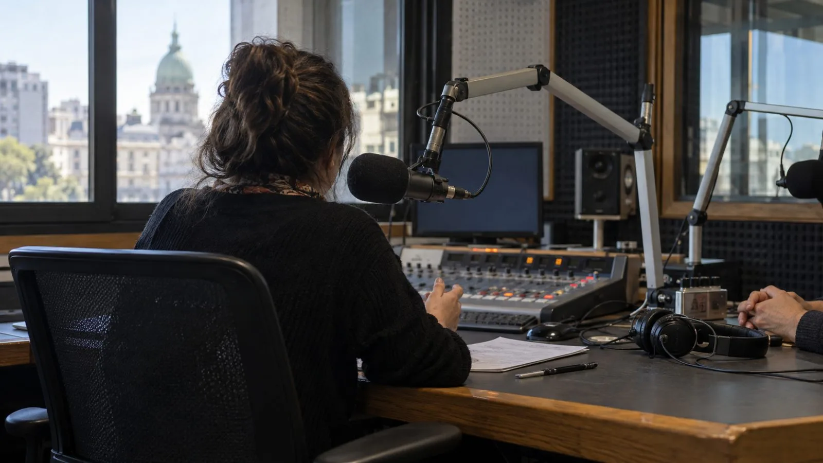 A broadcast microphone and headphones sit on a desk in a Buenos Aires radio studio. (AI-generated image / EconoTimes)