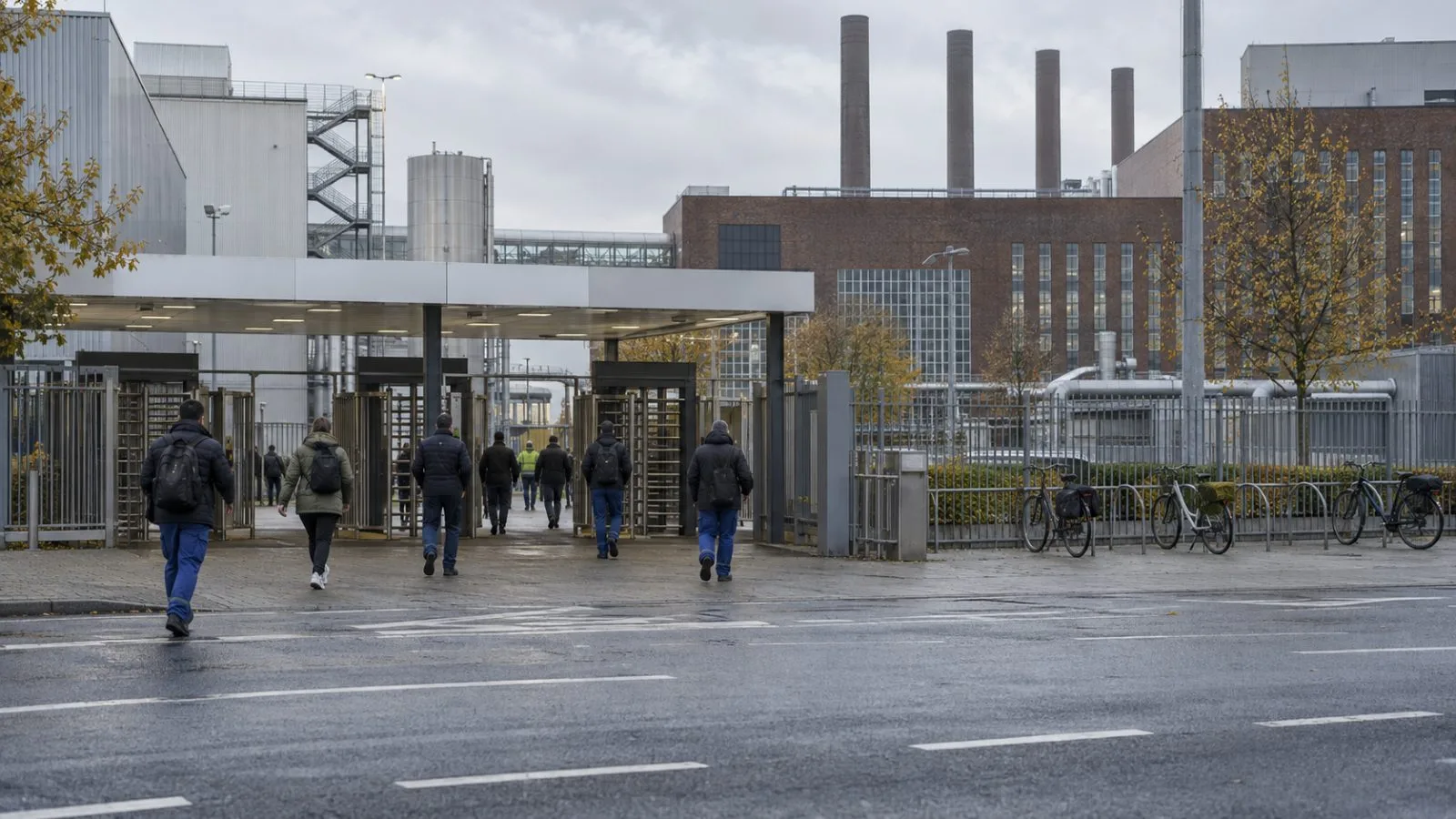 Workers enter a factory in Wolfsburg, Germany, under overcast morning skies. / EconoTimes.ai