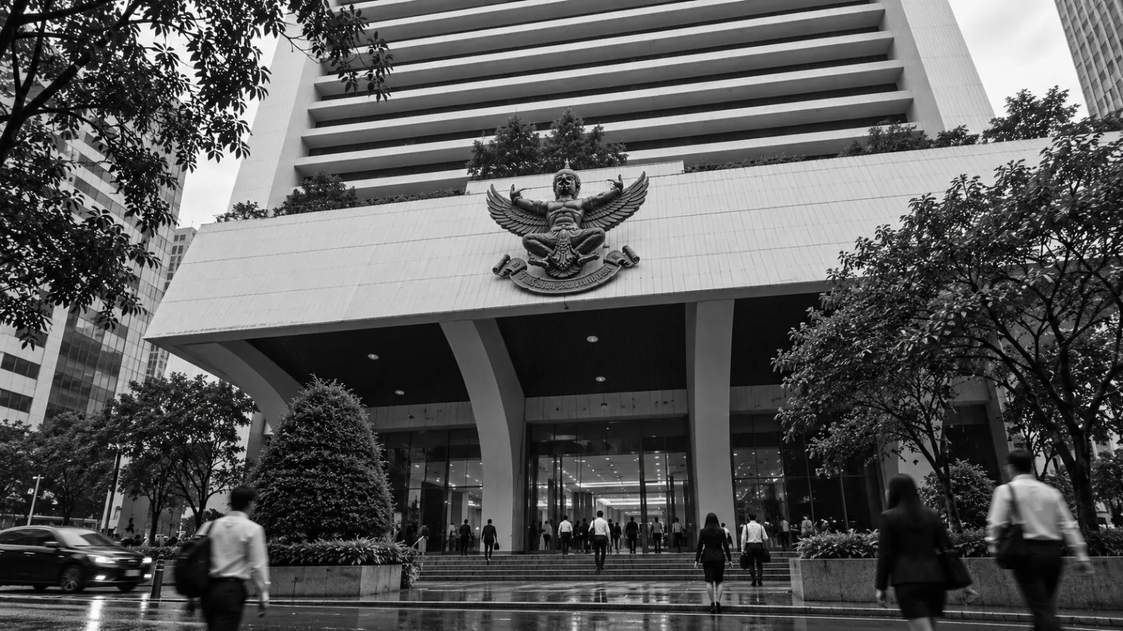 Office workers pass the Bangkok Bank headquarters on Silom Road in Bangkok. / EconoTimes.ai