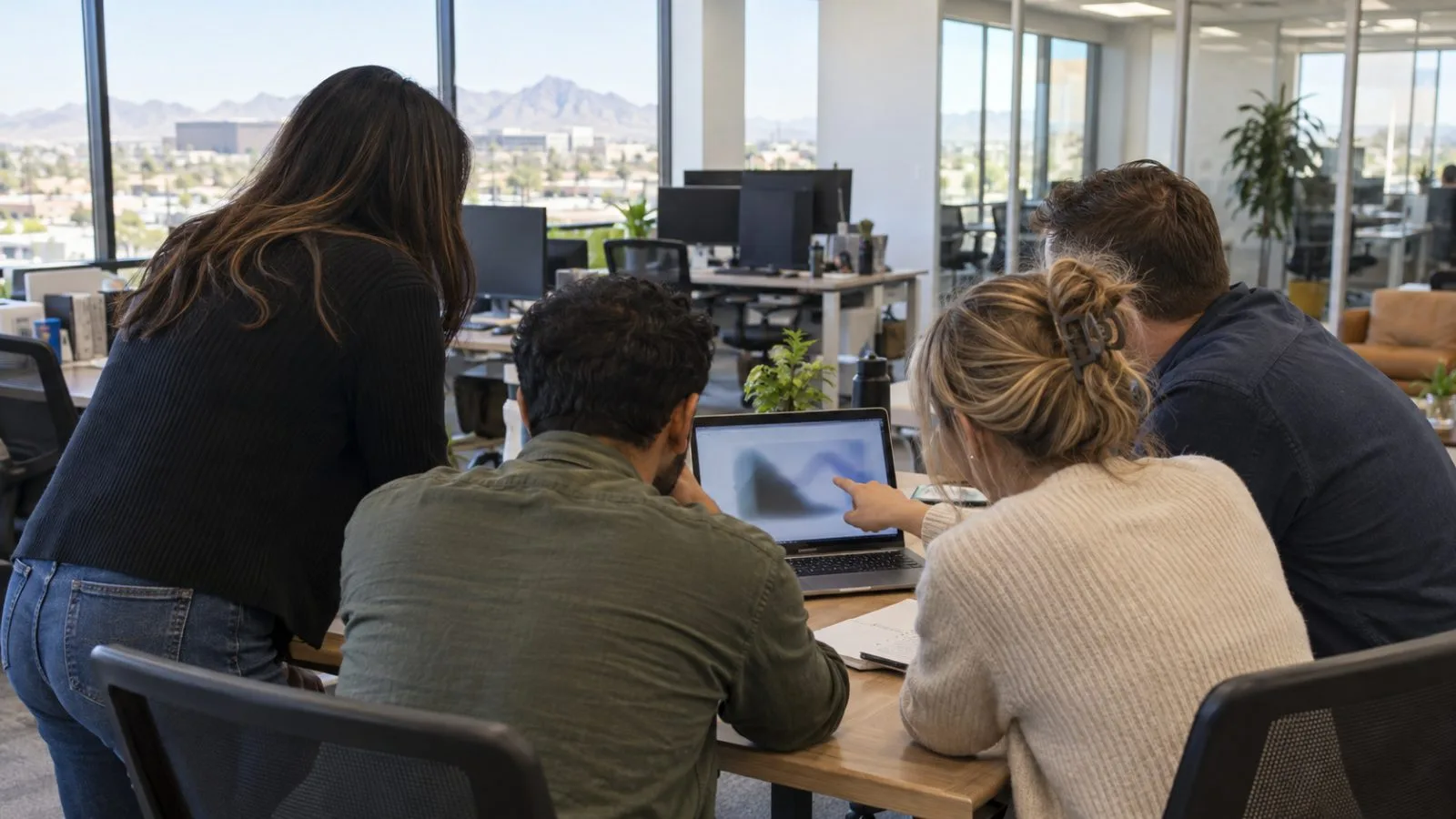 Technology specialists review a laptop during a work session in Chandler, Arizona. (AI-generated image / EconoTimes)