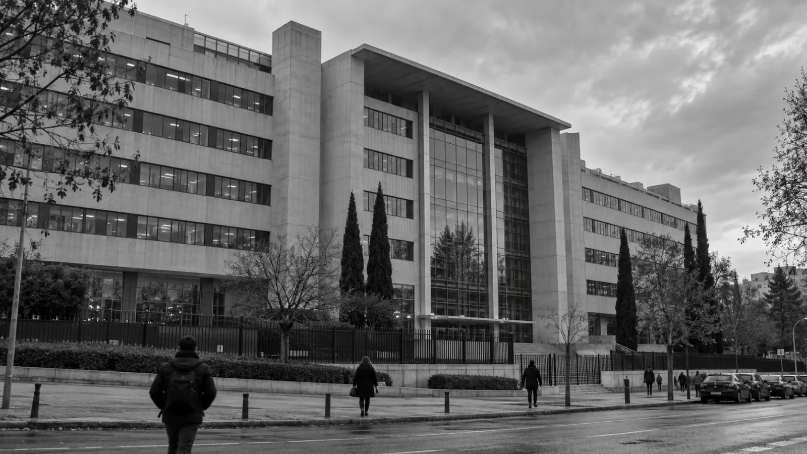 Pedestrians pass Spain’s National Statistics Institute headquarters in Madrid beneath a cloudy morning sky. (AI-generated image / EconoTimes)