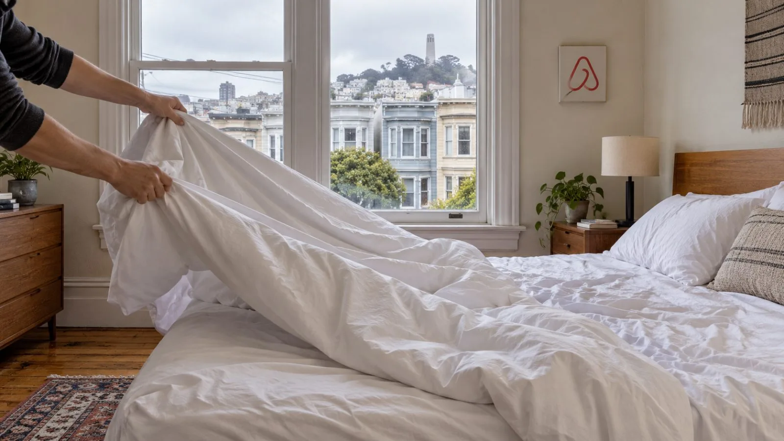 Hands remove a duvet cover in a short-term rental bedroom in San Francisco, California. / EconoTimes.ai