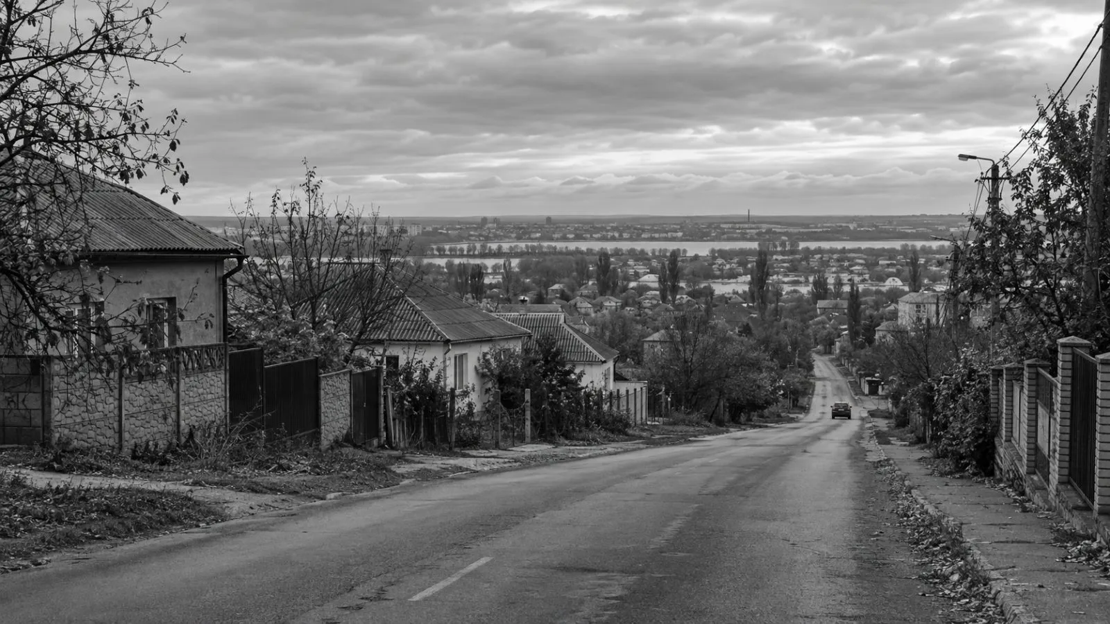A quiet road leads into Oleshky in Ukraine's Kherson region under gray autumn skies. (AI-generated image / EconoTimes)
